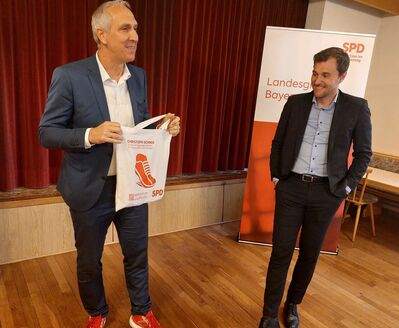 MdB Christoph Schmid überreicht MdB Johannes Schätzl einen Jutebeutel mit dem Logo "Läuft für Sie"